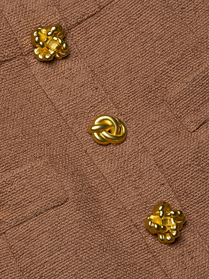 Close-up of the Wiley Tweed Mini Dress by L'AGENCE, showing textured brown fabric and three shiny gold statement buttons with unique designs arranged diagonally.