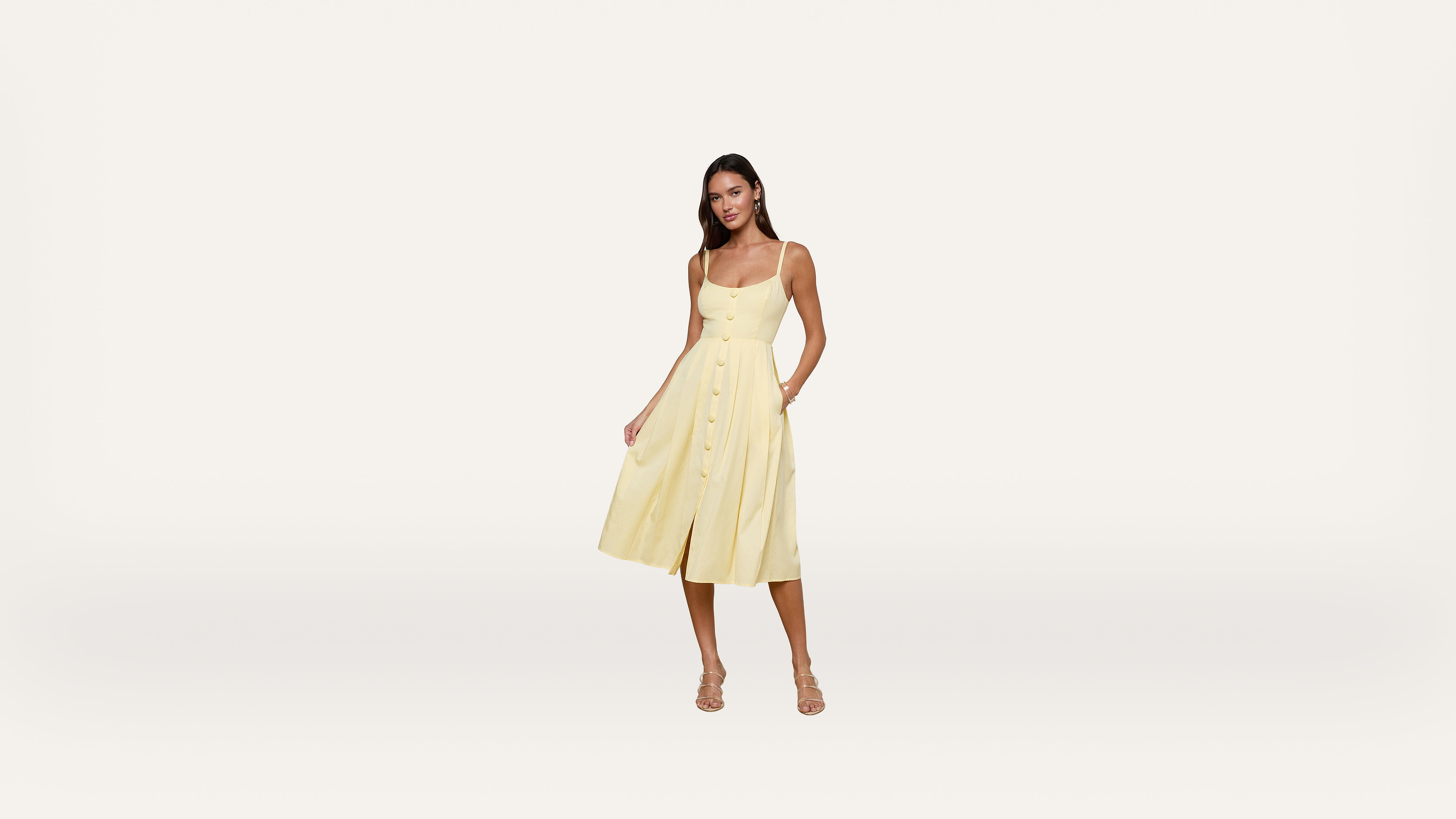 Woman wearing a sleeveless yellow midi dress with buttons down the front, standing and facing forward against a plain white background.