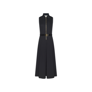 The Kolton Dress is a sleeveless, black cotton-blend midi dress with a collared neckline and front zipper closure. It features a fitted bodice, flared skirt, and a matching black belt at the waist. Shown against a plain white background, this dress highlights its center zip design.