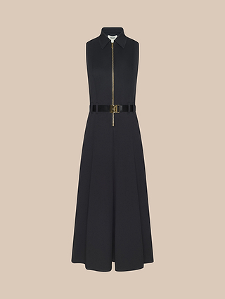 The Kolton Dress is a sleeveless black midi dress with a sleek center zip front, collared neckline, and fitted waist accented by a shiny adjustable belt, shown on a beige background.