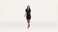 A woman in a navy blue, short-sleeved, buttoned dress and heels walks forward against a plain white background.