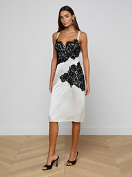 A woman poses confidently against a plain white background in the Fenna Silk Lace Dress, styled with black heeled sandals.