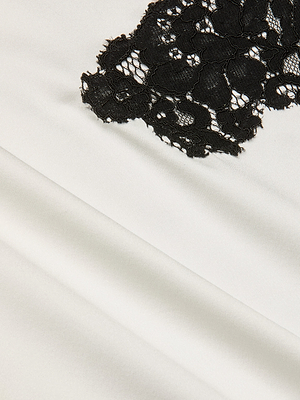 A close-up of smooth ivory silk charmeuse with delicate black lace overlay, echoing the refined elegance of the Fenna Silk Lace Dress.