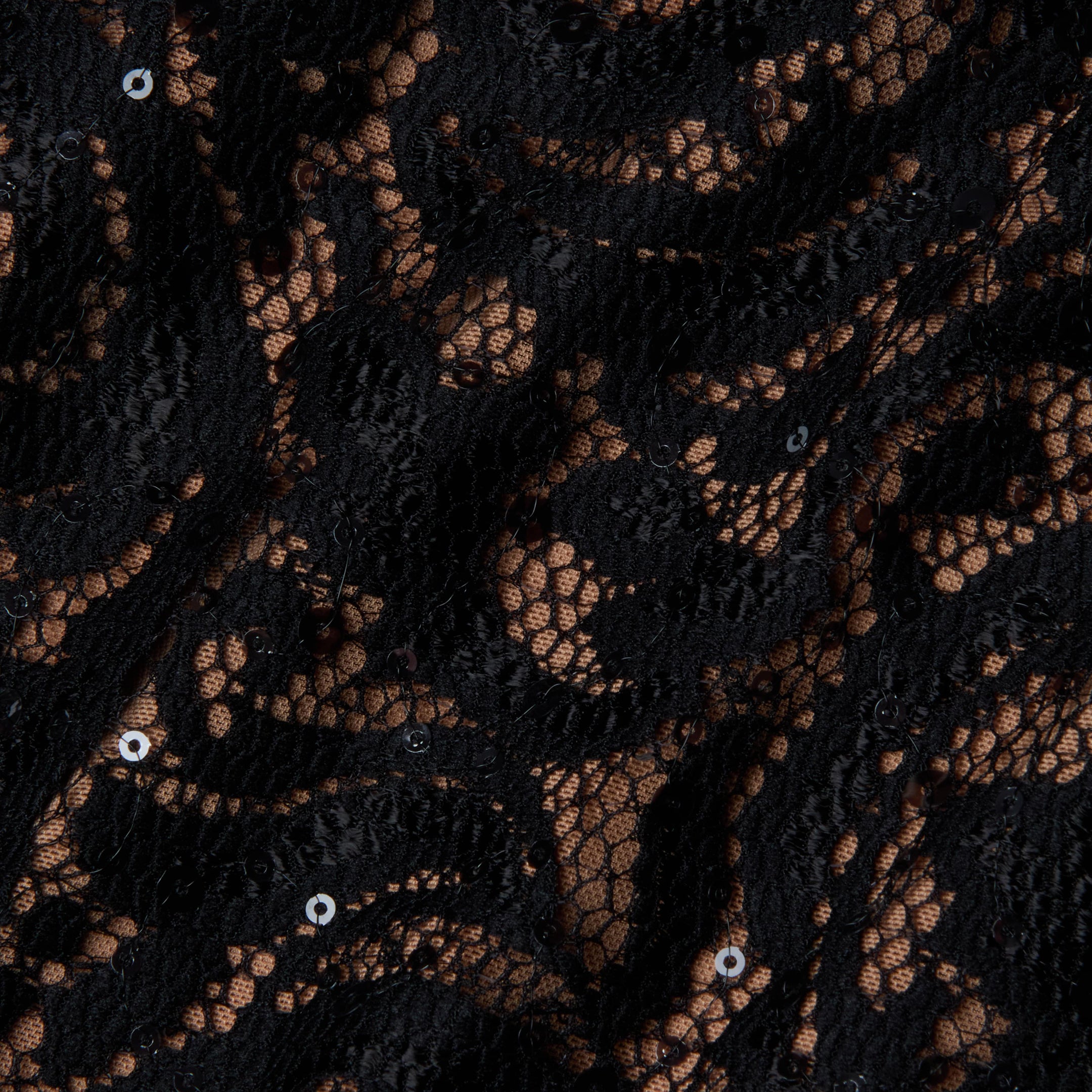 Close-up of the Lindsay Sequined Lace Dress, showcasing its intricate black lace fabric with a floral pattern, accented by small sequins and a nude-colored backing visible through the open mesh—perfect for an elegant off-shoulder evening look.