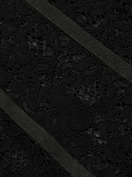Close-up of the Jennifer Lace Midi Dress, featuring textured sheer floral lace fabric adorned with two diagonally crossing black grosgrain ribbons. The intricate floral pattern of the lace is beautifully contrasted by the ribbed surface of the ribbons, highlighting the delicate details of the dress.