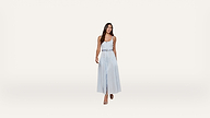 A woman wearing a light blue sleeveless dress and heels walks confidently against a plain white background.