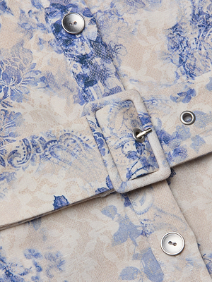 Close-up of the Kiersten Dress, a linen piece with beige and blue floral print, featuring a matching fabric belt with rectangular buckle, silver grommets, and buttons.