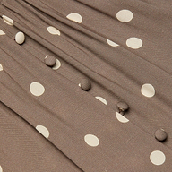 Close-up of the Rosette Maxi Dress featuring brown fabric with white polka dots, fabric-covered buttons in a row, and gathered pleats that highlight its summer-ready style.