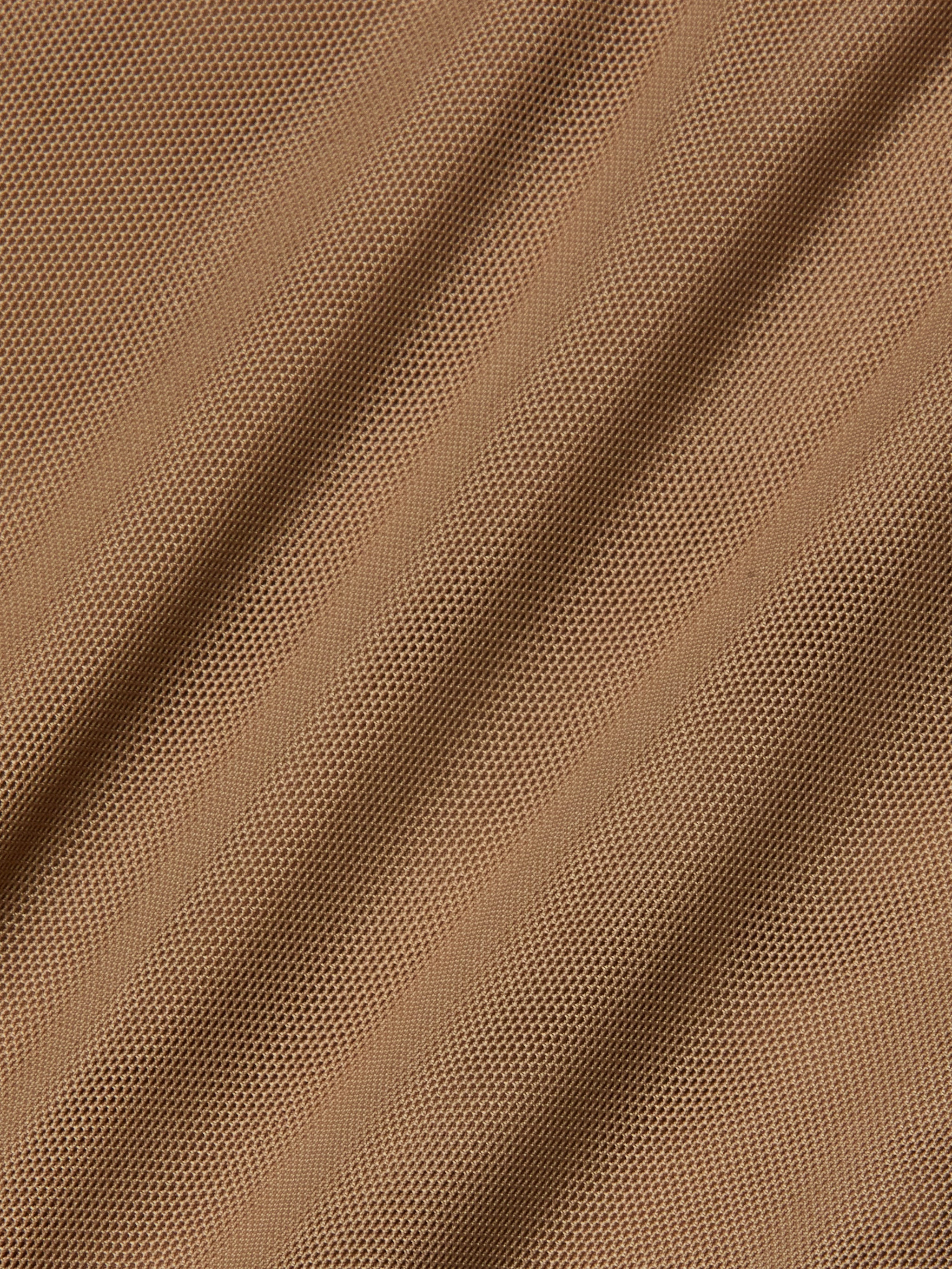 Close-up of light brown stretch mesh fabric with diagonal folds and visible small holes, creating a textured and patterned surface often used as bodysuit lining for garments like the Sorella Mesh Midi Dress.