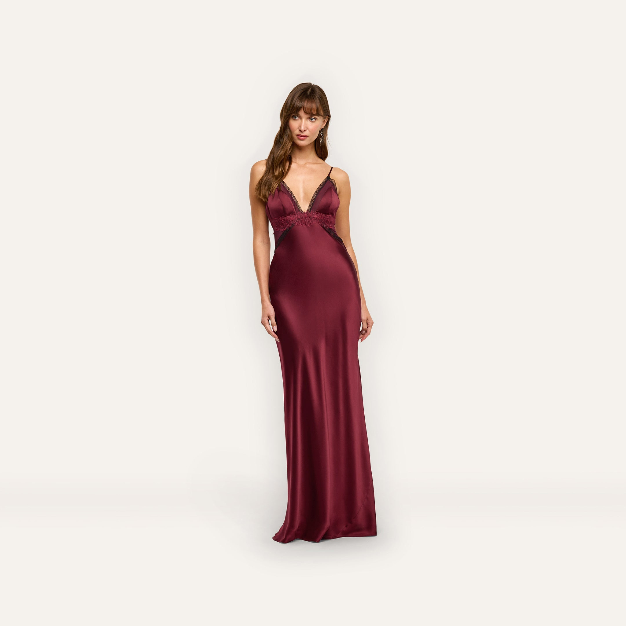 A person wearing an Elsa Silk Gown in deep red silk with a V-neckline and lace accents.