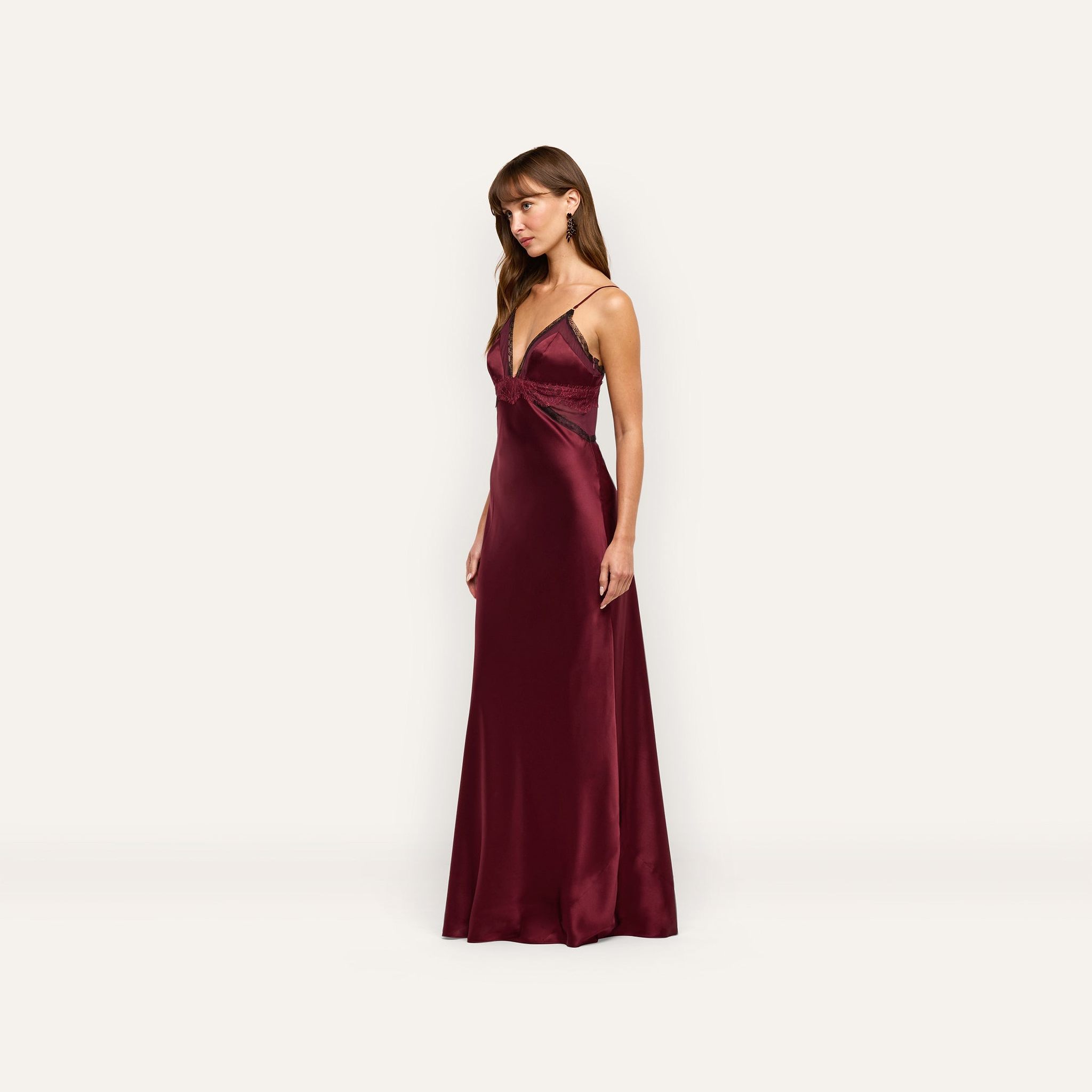 The Elsa Silk Gown is a floor-length deep burgundy silk slip dress with a V-neckline, thin straps, and black lace accents.