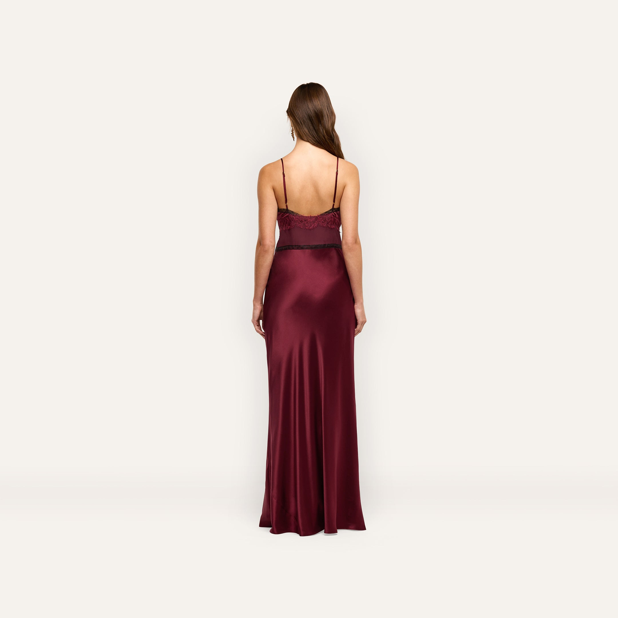 Back view of the Elsa Silk Gown, a floor-length burgundy silk slip dress with thin straps and black lace accents at the bodice.