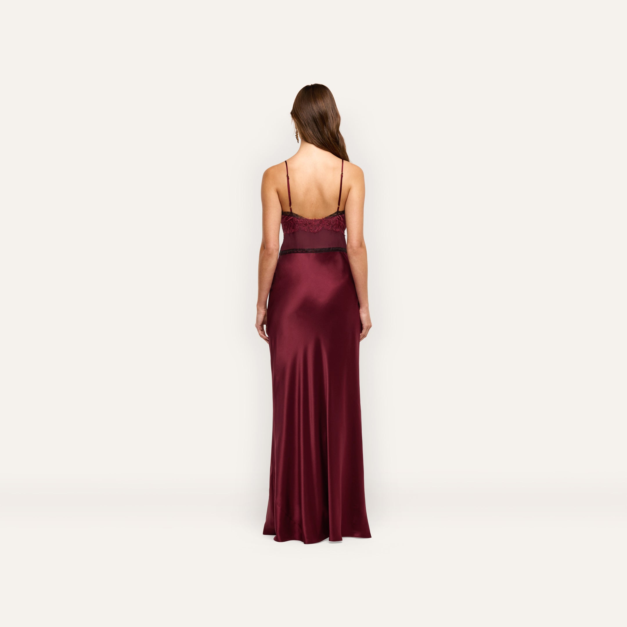 Back view of the Elsa Silk Gown, a floor-length burgundy silk slip dress with thin straps and black lace accents at the bodice.
