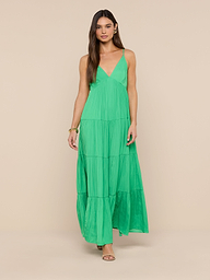 A woman in the Lua Tiered Maxi Dress—a sleeveless, long green maxi dress with adjustable straps—stands facing forward against a plain white background. The crinkle-effect satin fabric adds subtle texture to the elegant look.