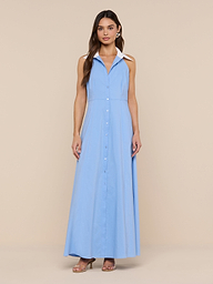 A woman wears the sleeveless, light blue Maurie Poplin Maxi Dress with a collar, crafted from an organic cotton-blend fabric, standing against a plain white background and paired with brown heeled sandals.
