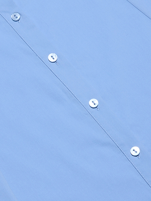 A close-up of the Maurie Poplin Maxi Dress in light blue organic cotton poplin, featuring white buttons and detailed stitching along the placket. The fabric looks smooth and neatly pressed.