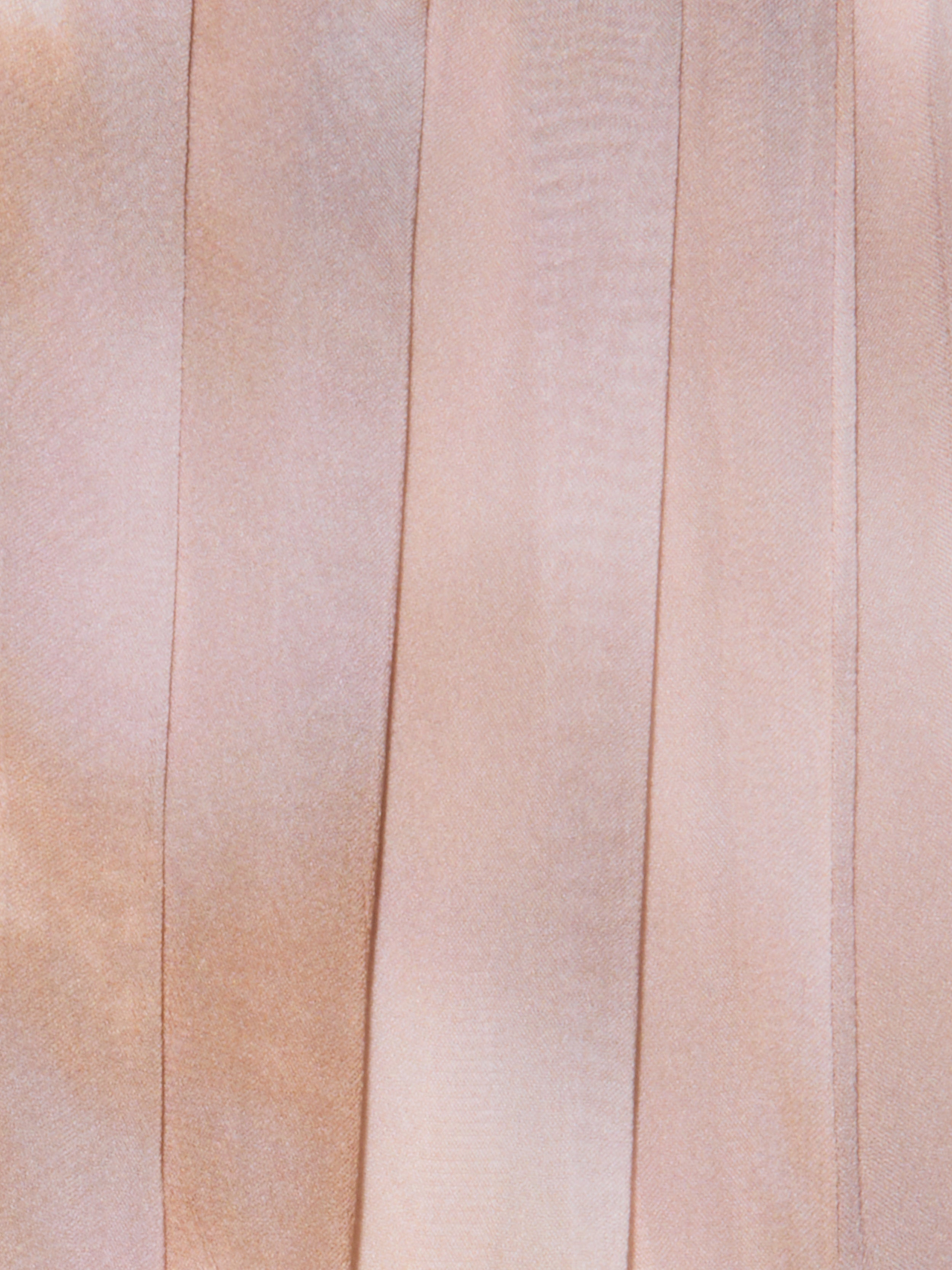 Close-up of light pink satin ribbons laid vertically side by side, highlighting their smooth, lustrous texture and delicate shifts in color and sheen—evocative of the elegant detailing found on a pleated dress or the sophisticated finish of the Raine Strapless Gown’s built-in corset.