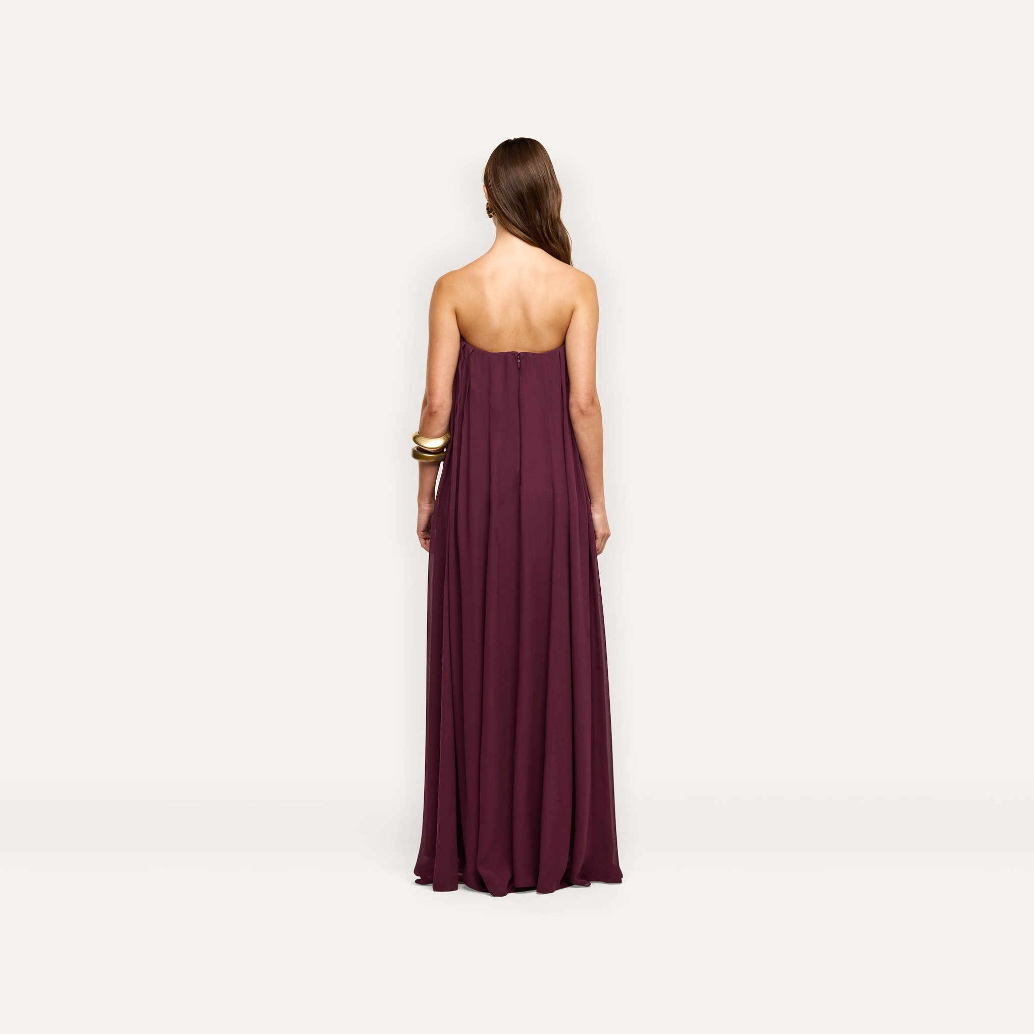 Back view of a floor-length, plum-colored Raine Strapless Gown in viscose chiffon, featuring a strapless design with a relaxed fit and a built-in corset.