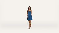 A woman in a blue denim dress and blue shoes walks toward the camera against a plain white background.