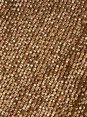 Close-up of the Paula Gown's fabric, densely adorned with sequin bead embellishments sewn in neat rows, forming a sparkling, textured pattern on a brown background.