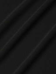 Close-up of the Raye Slip Lining Dress in black stretch jersey fabric, featuring diagonal, evenly spaced folds that create a soft and subtle textured pattern. The surface appears smooth and matte, with shadows accentuating the gentle contours of the dress’s pleats.