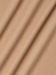 Light brown stretch jersey fabric forms the Raye Slip Lining Dress, its softly draped folds lending gentle shadows and textured dimension across the surface.