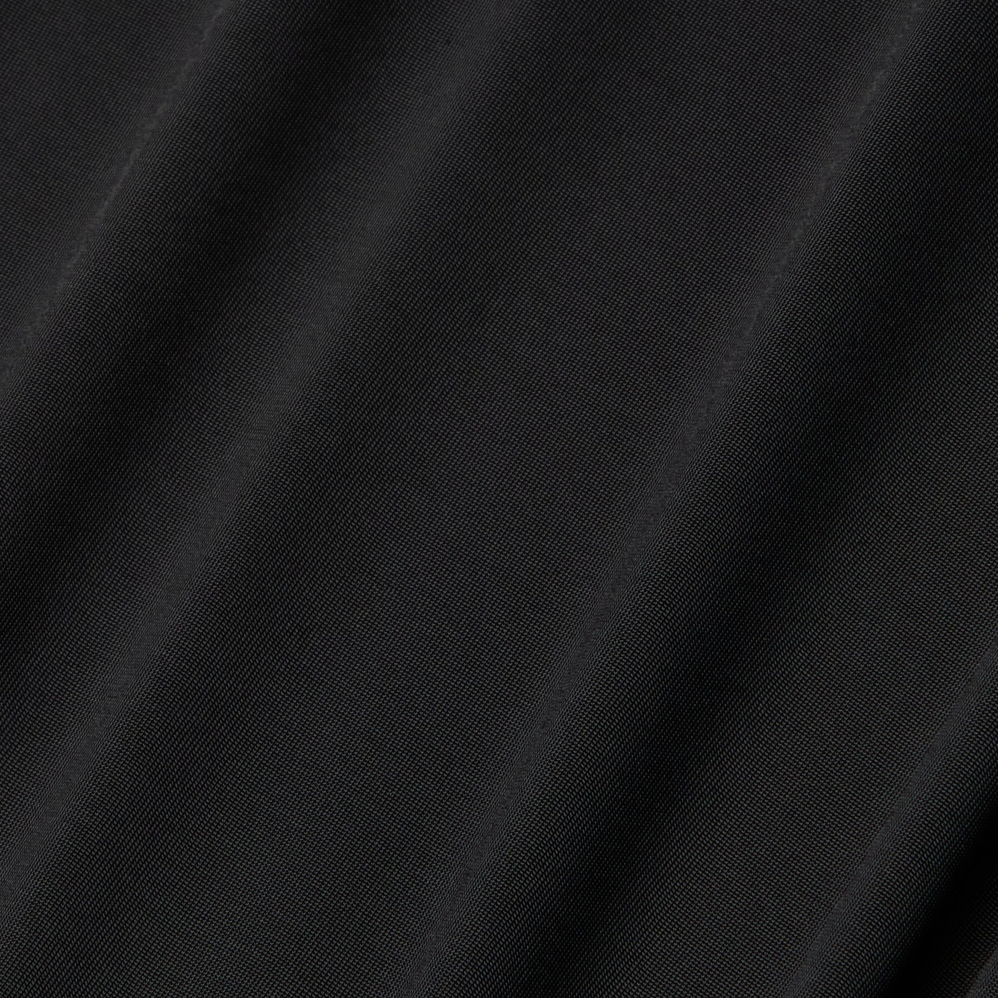 Close-up of the Raye Slip Lining Dress in black poly georgette fabric, featuring subtle diagonal folds that highlight its smooth texture and slight sheen under the light.