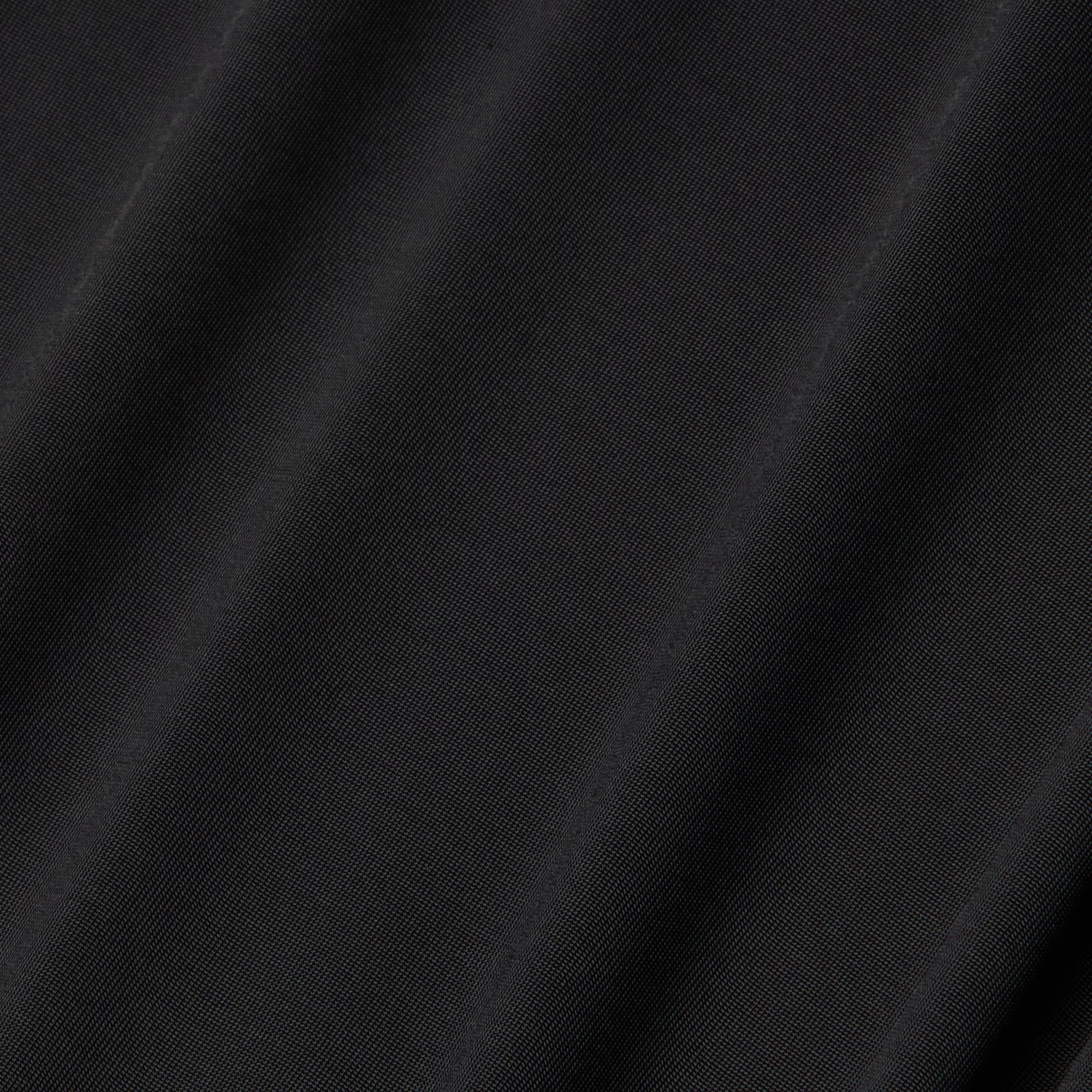 Close-up of the Raye Slip Lining Dress in black poly georgette fabric, featuring subtle diagonal folds that highlight its smooth texture and slight sheen under the light.