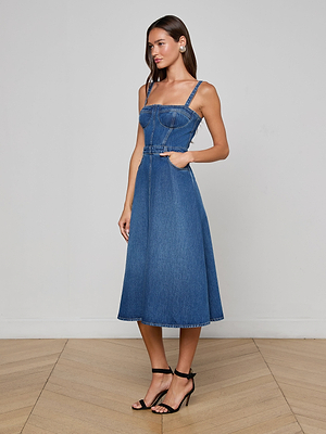 A woman wearing the Jovie Bustier Dress, featuring a blue denim corset-inspired bodice and an elegant A-line skirt.