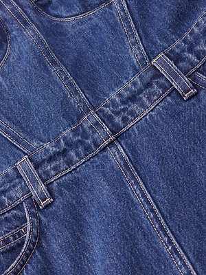 Close-up of blue denim from the Jovie Bustier Dress, featuring belt loops, stitching, and a pocket detail that showcases the texture and construction of the fabric.