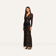 A woman poses in the Poesy Lace Maxi Dress, a black maxi-length gown featuring long sleeves and paired with black heels, set against a plain light background.