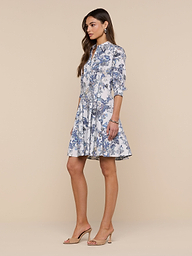 A woman stands against a plain white background, looking to the side with her hands at her sides, wearing the Journi Shirt Dress and beige heels.