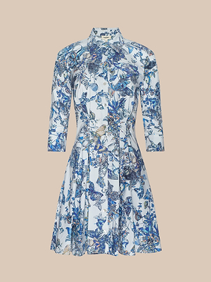 The Journi Shirt Dress is a knee-length cotton-blend poplin shirt dress with three-quarter sleeves and a flared skirt, featuring a blue and white floral and butterfly print on a light background, shown against a plain beige backdrop.