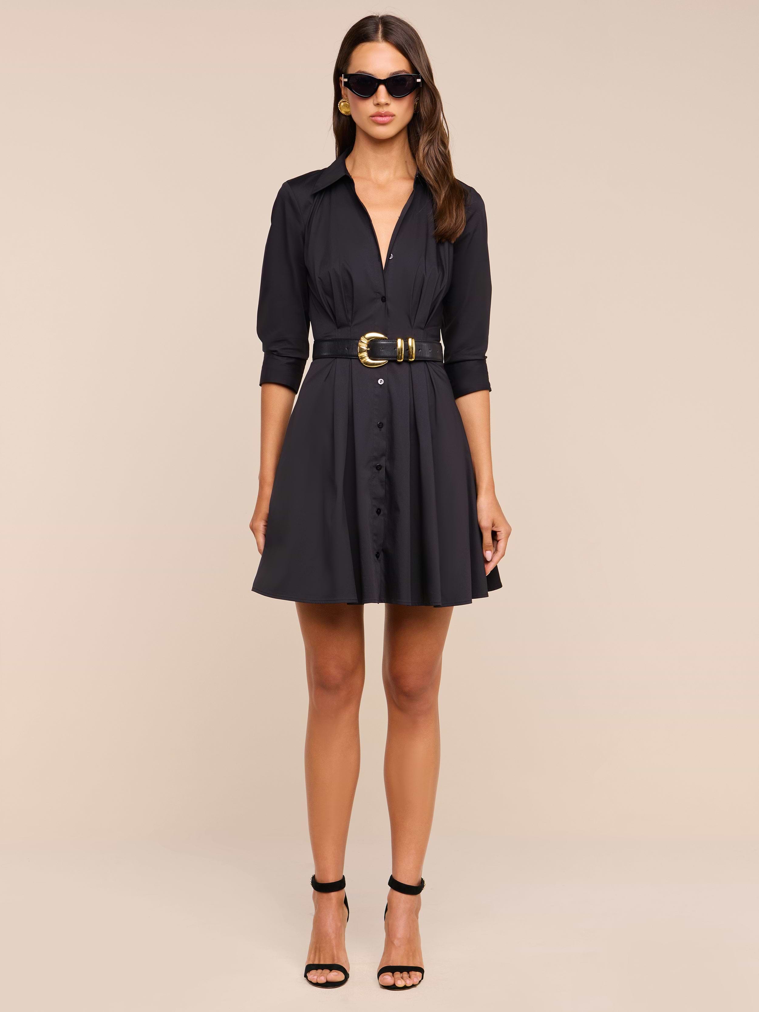 A woman wearing the Journi Shirt Dress, styled with black high-heeled sandals and sunglasses, stands against a plain white background.