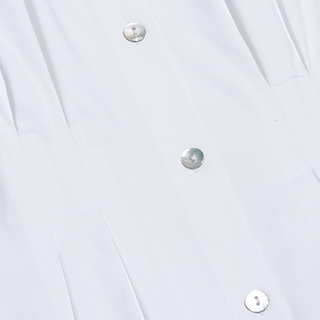 Close-up of the Journi Shirt Dress in white, featuring shiny, round buttons arranged vertically down the center. The smooth stretch cotton-blend fabric is subtly pleated near the buttons, suggesting a classic silhouette.