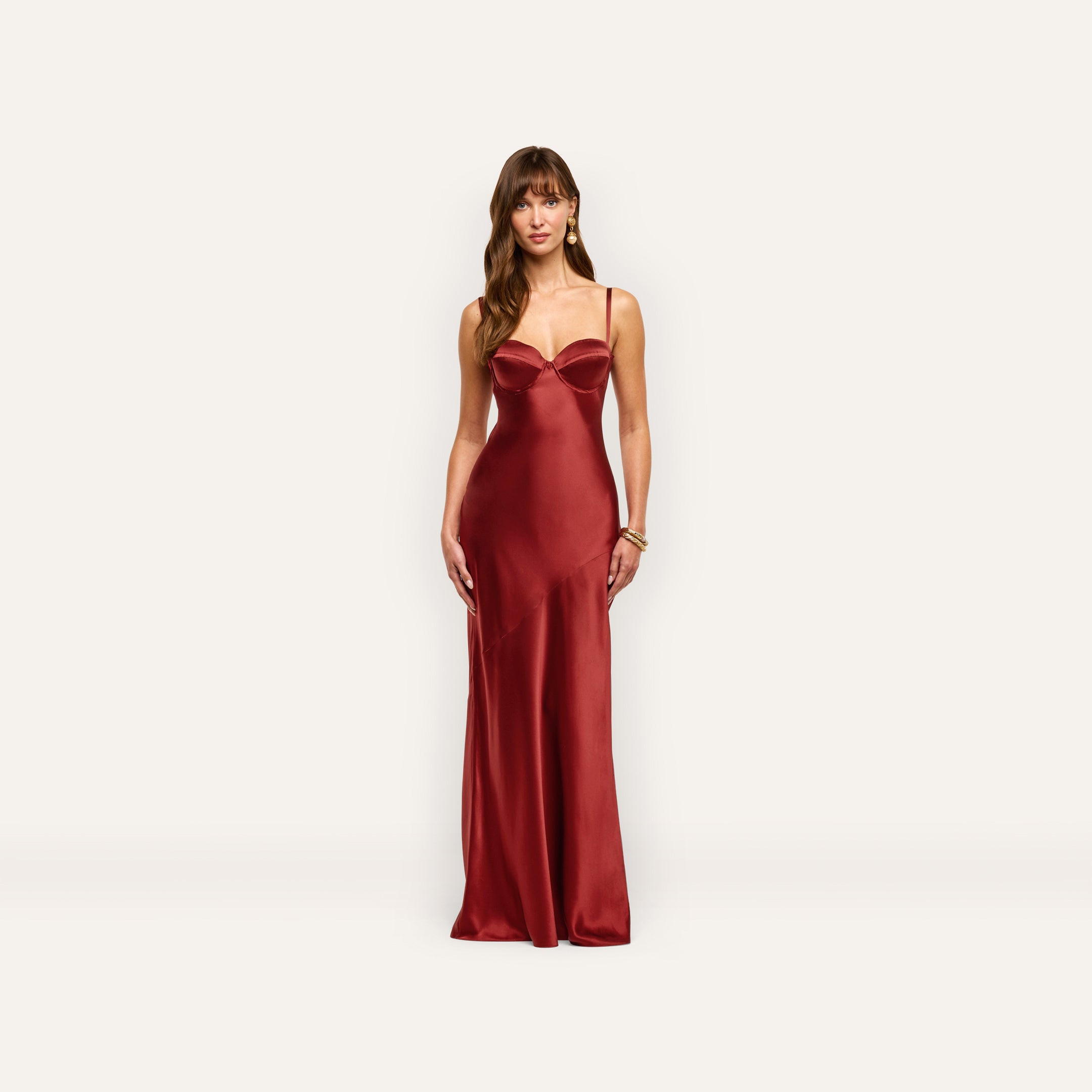 A woman in a deep red silk Sayla Silk Gown with thin straps and a structured bodice, evoking vintage glamour.