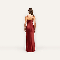 A person seen from behind, wearing a floor-length, burgundy Sayla Silk Gown with spaghetti straps that evokes vintage glamour.