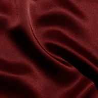 Deep red silk fabric of the Sayla Silk Gown draped in soft folds with vintage glamour.