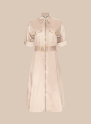 The Callen Shirt Dress is a beige, short-sleeved, stretch cotton-blend dress with rolled cuffs, an exposed front zip, gold chest pocket buttons, and a matching belt with gold buckle, shown on a plain beige background.