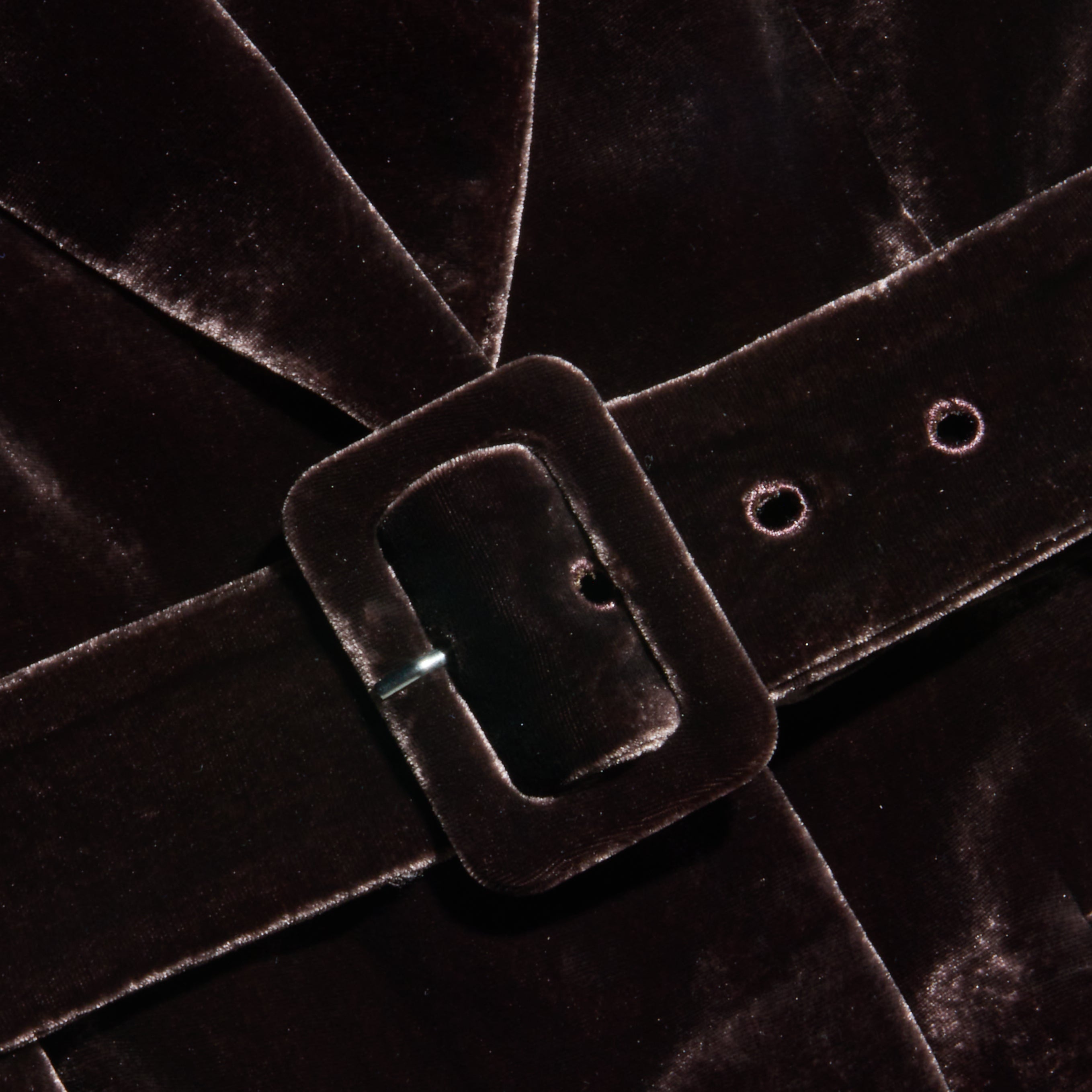 Close-up of the Raini Velvet Maxi Dress in dark brown, featuring a matching velvet belt with a rectangular buckle fastened around the waist. The soft, slightly reflective texture of the luxurious velvet fabric highlights elegant details, making this dress perfect for Fall 2026 fashion.