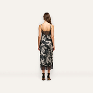 A person viewed from behind wearing a Victoire Silk Dress, a mid-length silk slip dress with a black and white magazine print and black lace trim at the neckline and hem.