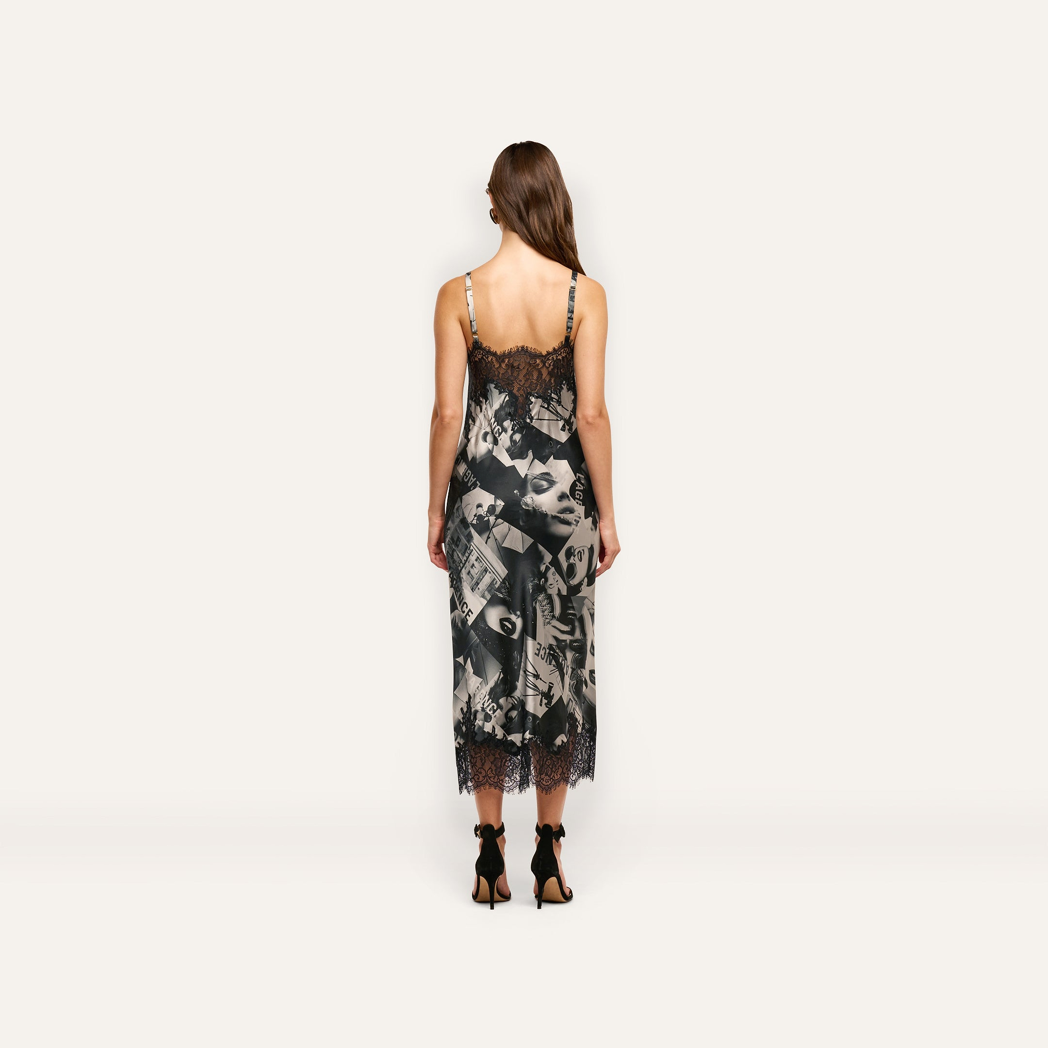A person viewed from behind wearing a Victoire Silk Dress, a mid-length silk slip dress with a black and white magazine print and black lace trim at the neckline and hem.