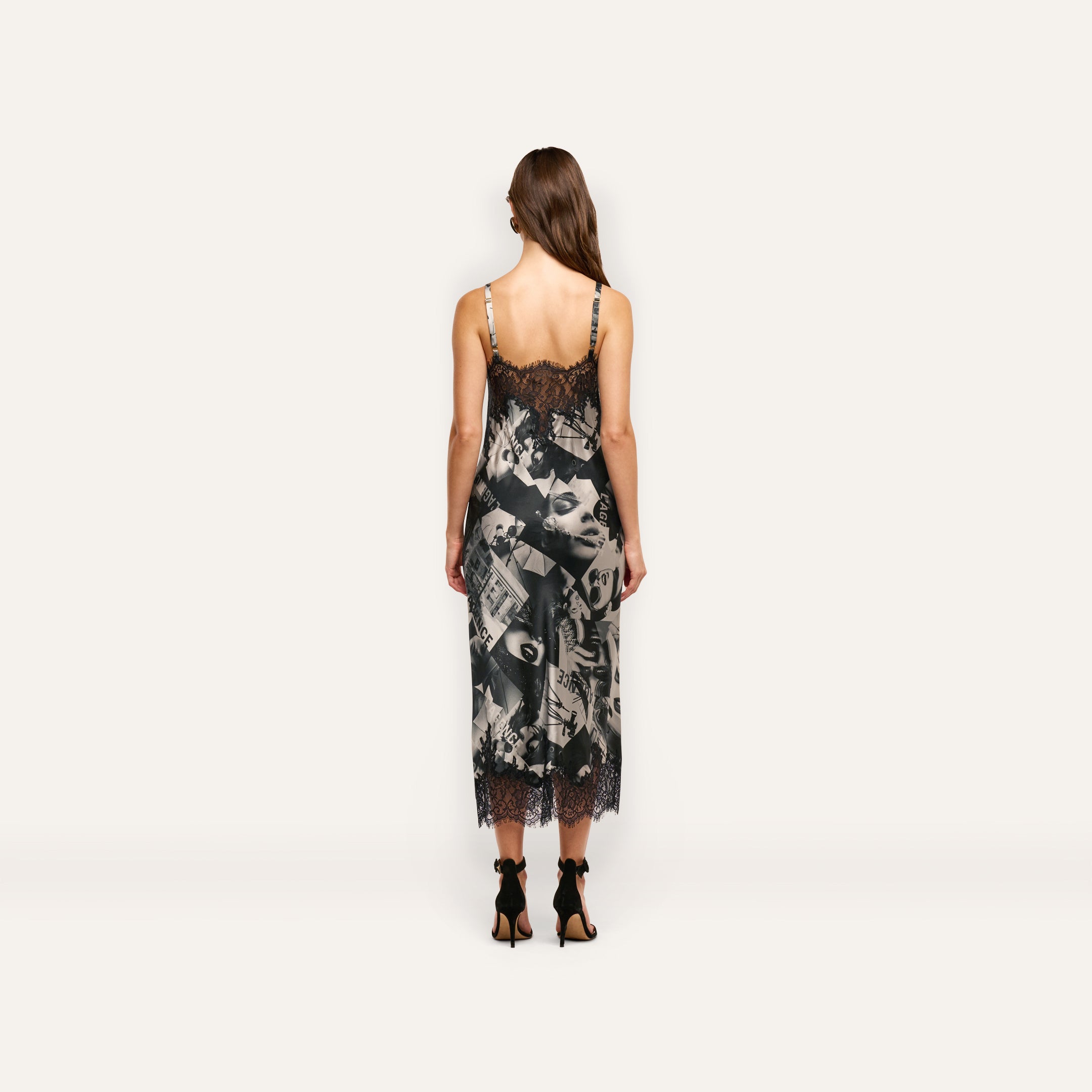 A person viewed from behind wearing a Victoire Silk Dress, a mid-length silk slip dress with a black and white magazine print and black lace trim at the neckline and hem.
