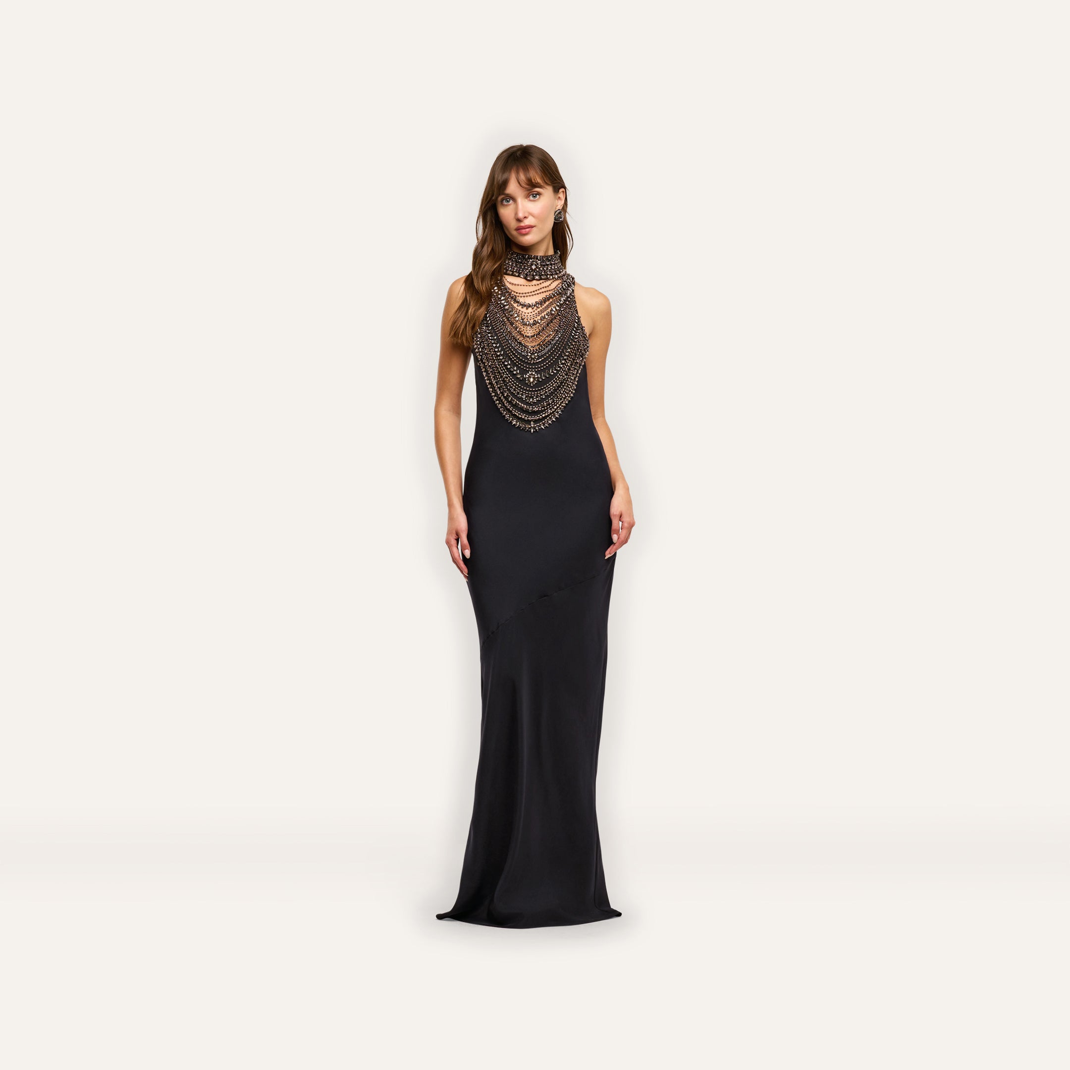 The Yuan Embellished Gown is a floor-length black satin maxi dress featuring a high, crystal-embellished, multi-layered beaded necklace collar draped over the chest.