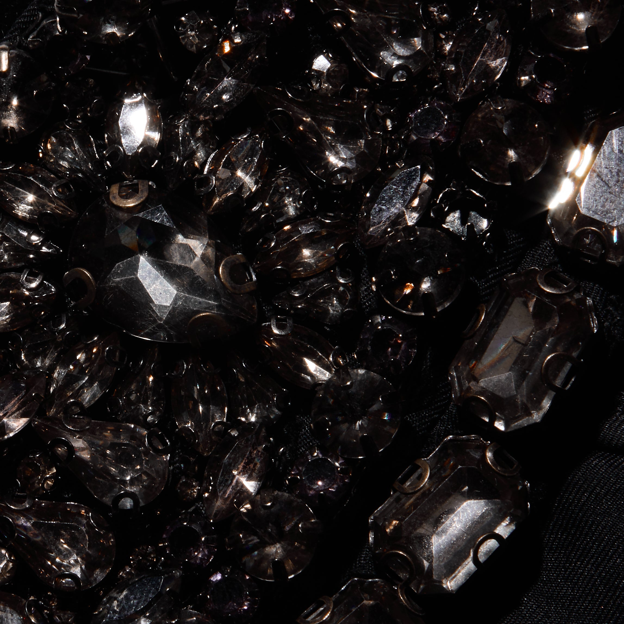 Close-up of black faceted crystals and teardrop-shaped stones sewn onto the satin fabric of a Yuan Embellished Gown.