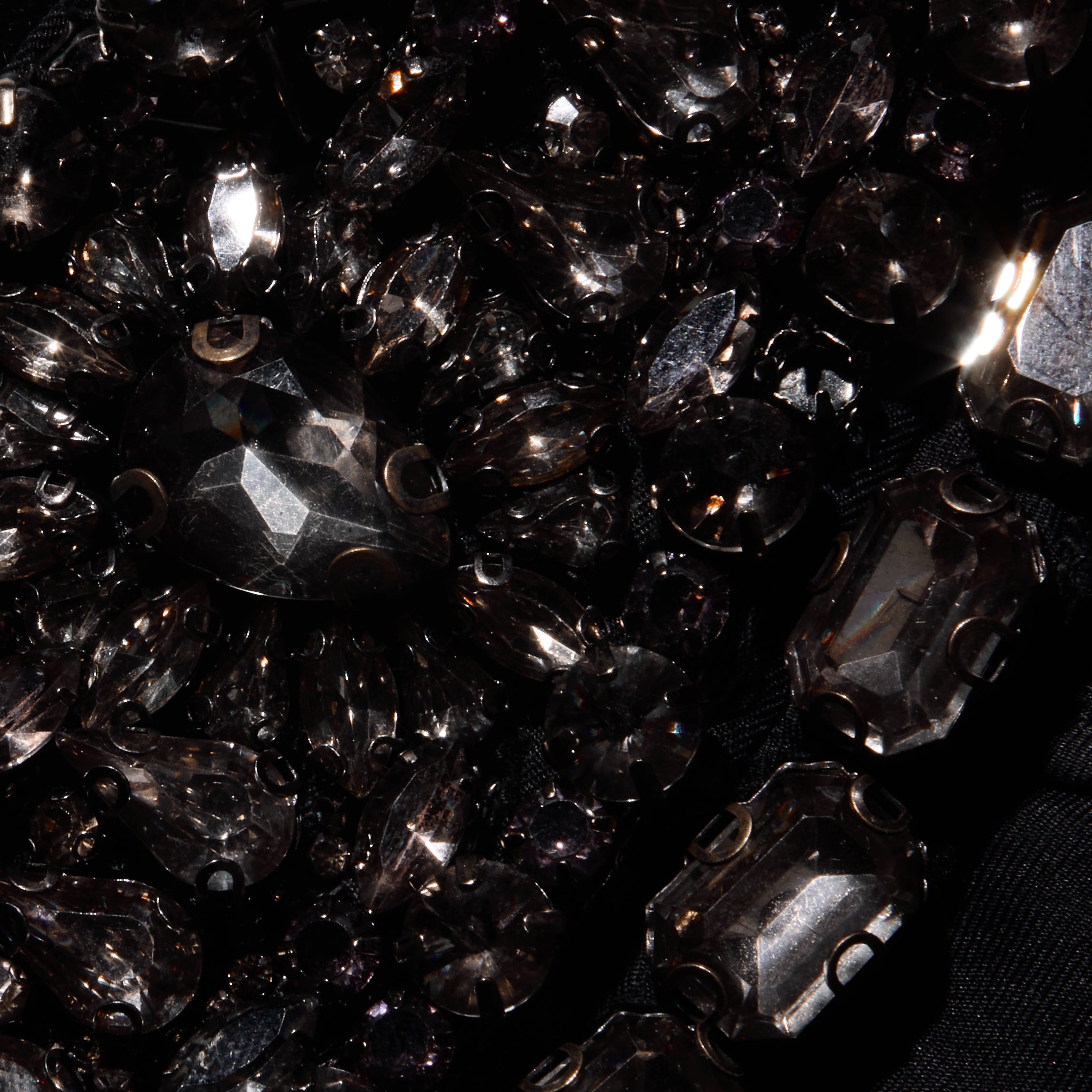 Close-up of black faceted crystals and teardrop-shaped stones sewn onto the satin fabric of a Yuan Embellished Gown.
