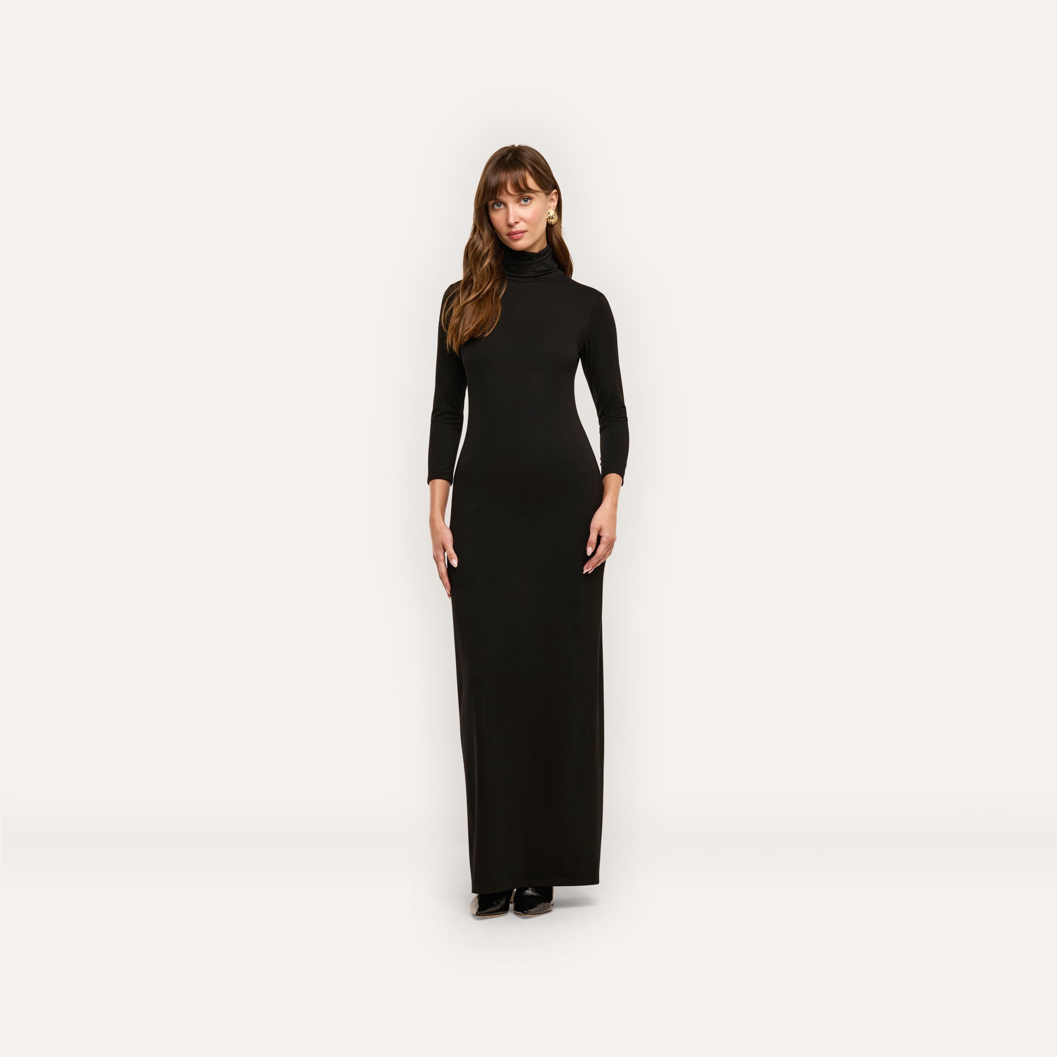 A woman wearing the black turtleneck Jaesyn Dress with three-quarter length sleeves.