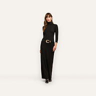 A woman wears a long-sleeved black jersey knit Jaesyn Dress turtleneck maxi dress with a black belt featuring a decorative gold buckle.