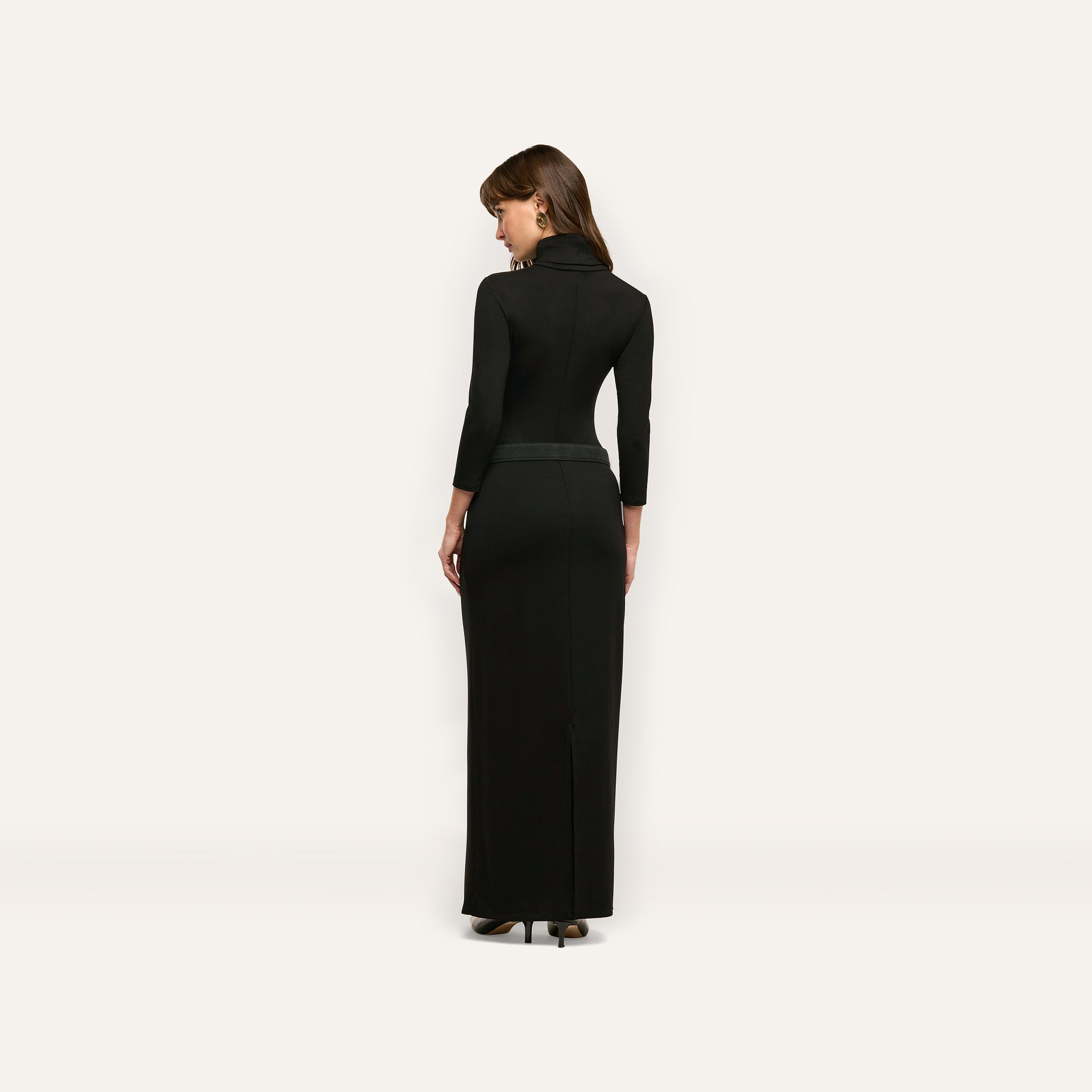 A person viewed from behind wearing a black, long-sleeved Jaesyn Dress that falls to the floor.