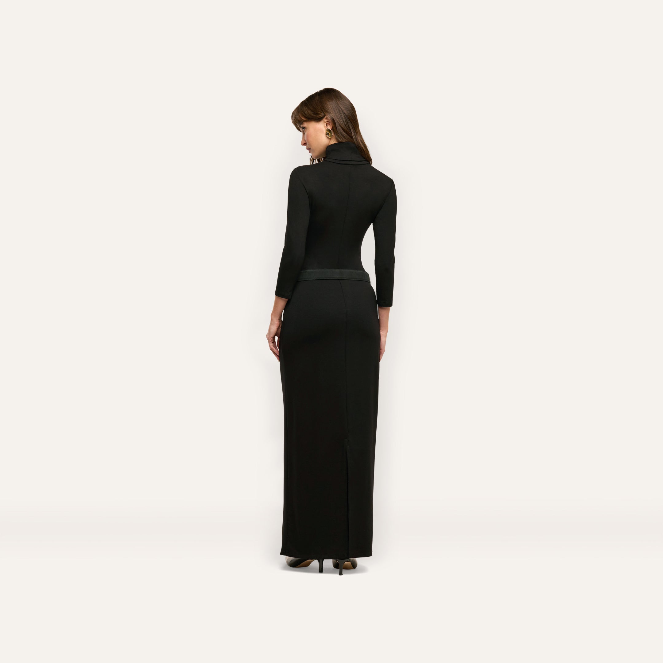 A person viewed from behind wearing a black, long-sleeved Jaesyn Dress that falls to the floor.